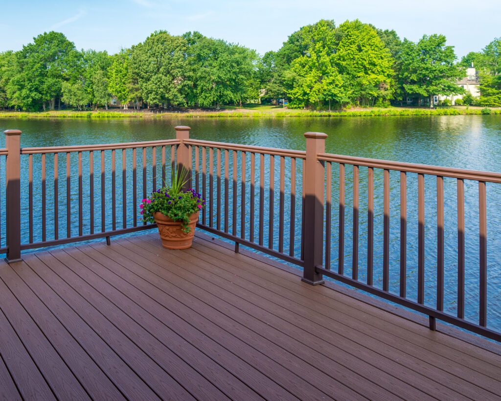 Spacious brown deck with black railing and cozy seating surrounded by trees