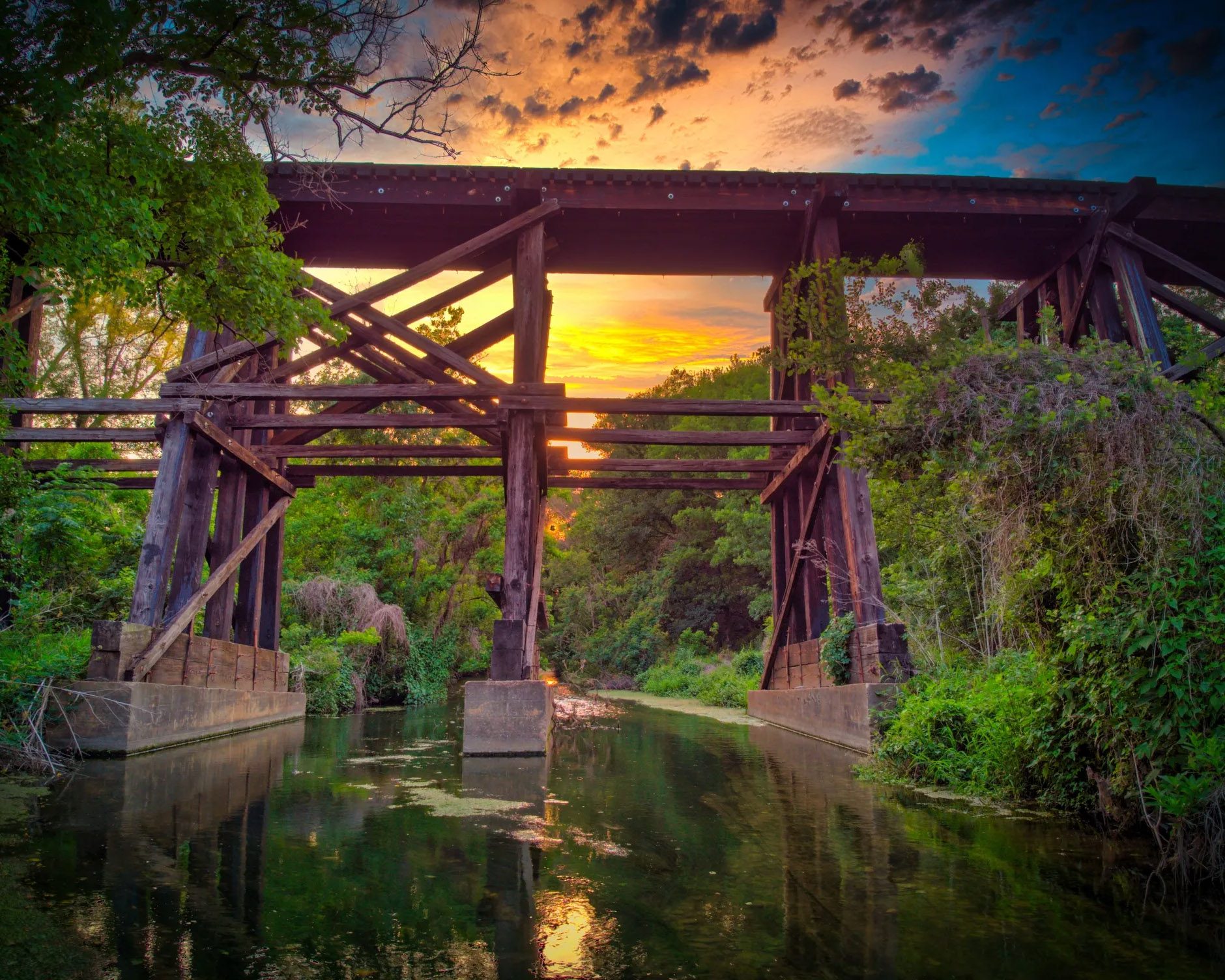 Scenic Cedar Park bridge at sunset near Trinity Fence and Deck builds Railroad bridge at dusk in Cedar Park with trees and creek—local scene near Trinity Fence and Deck projects