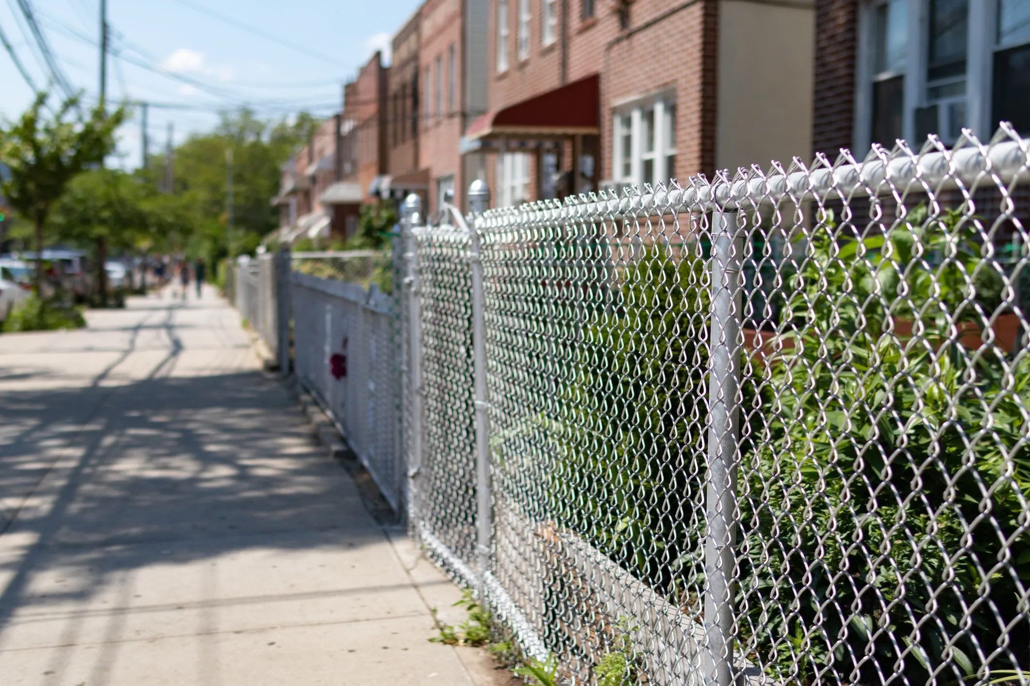 Chainlink fence installed along a narrow commercial walkway between buildings.