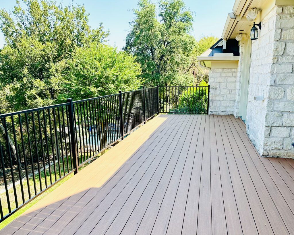 Elevated composite deck with black metal railing and limestone home exterior