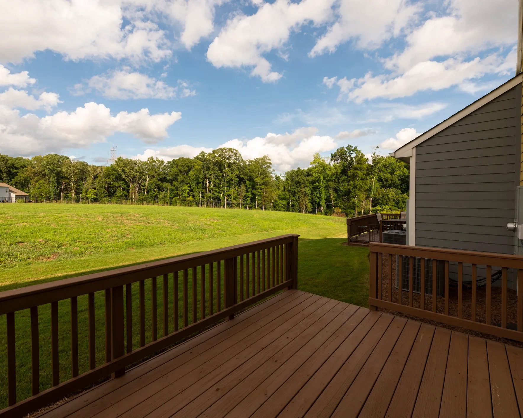 Wide-angle view of stained backyard deck under a clear blue sky.
