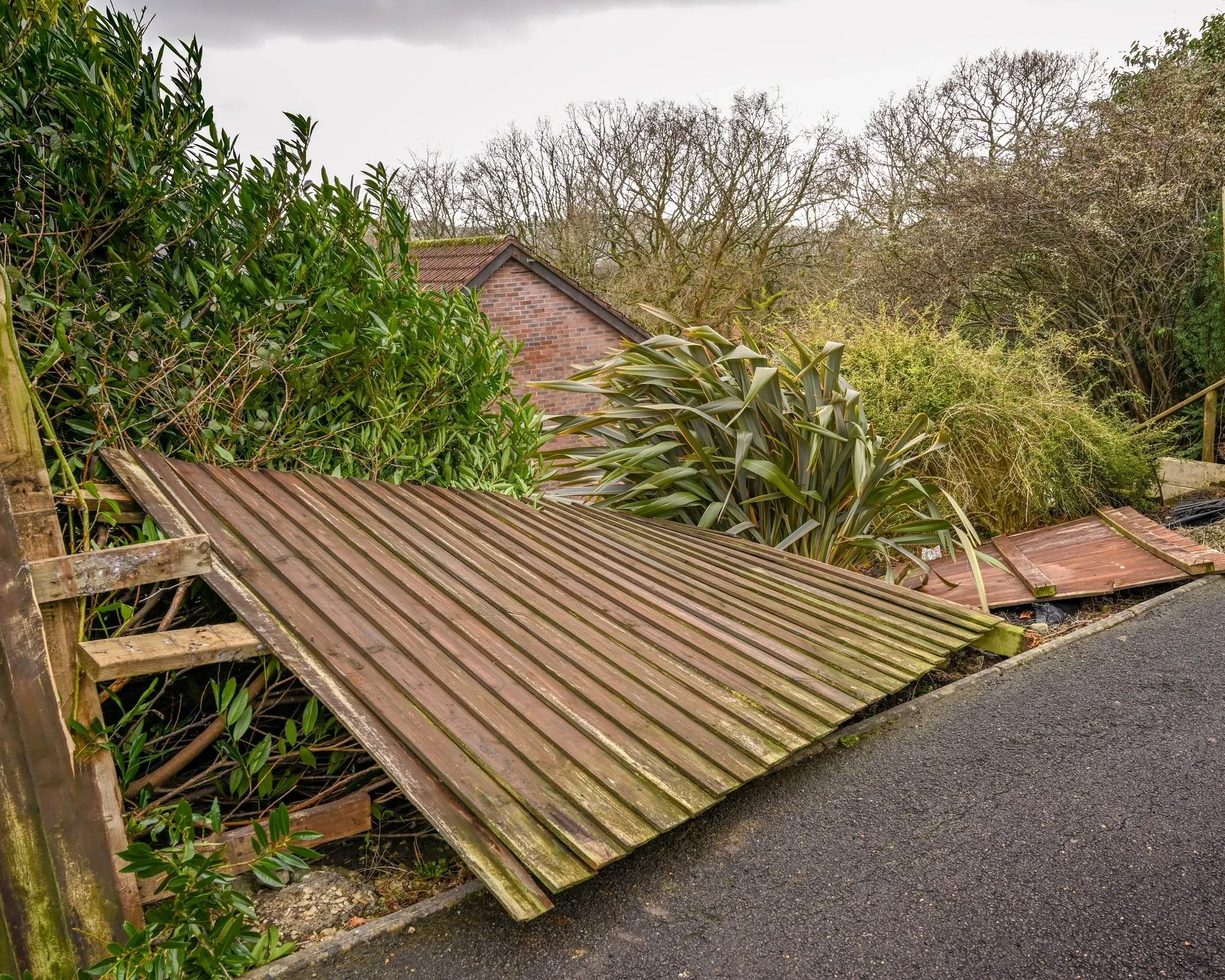 Damaged wood fence leaning after storm damage