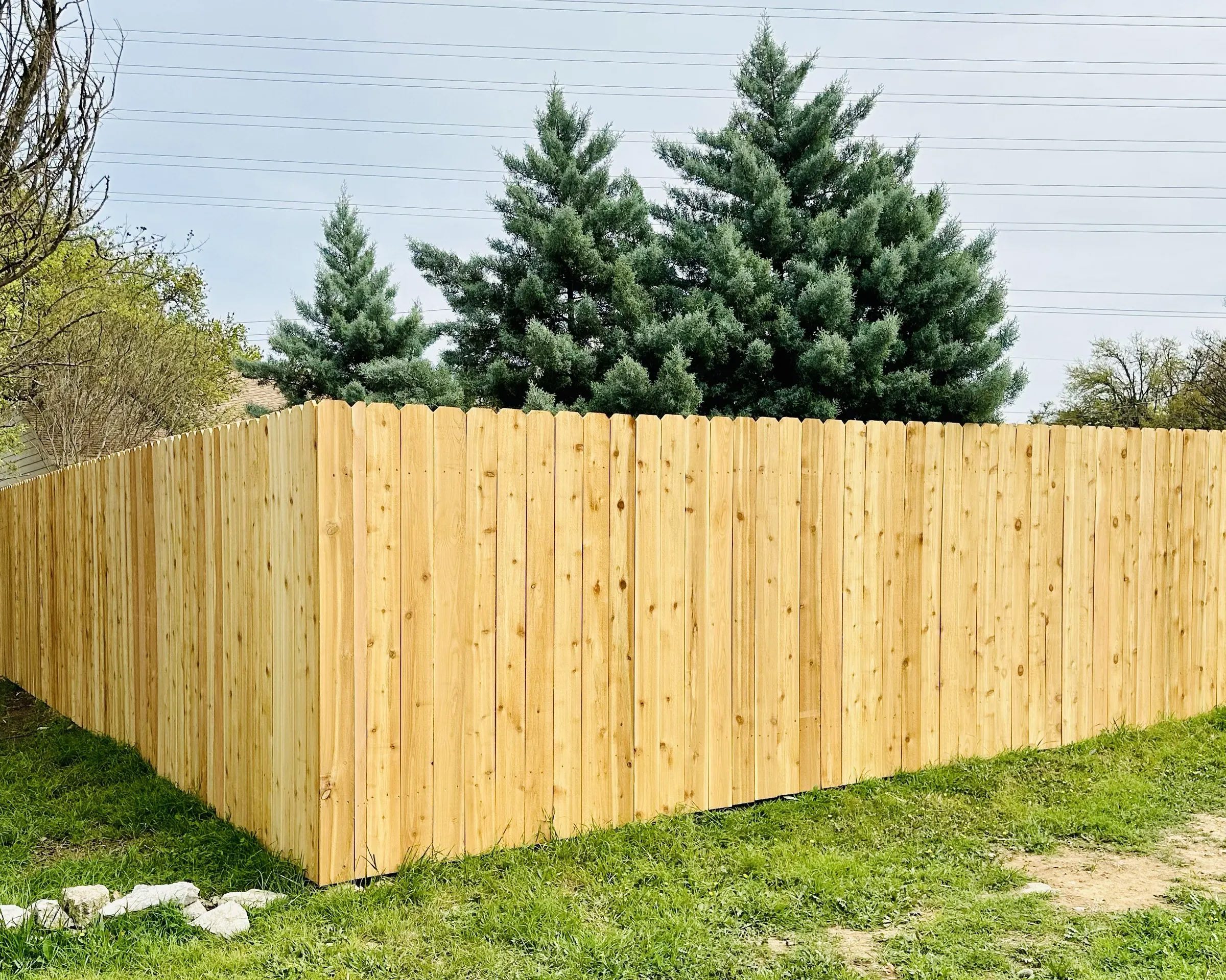 Standard vertical cedar privacy fence enclosing green lawn