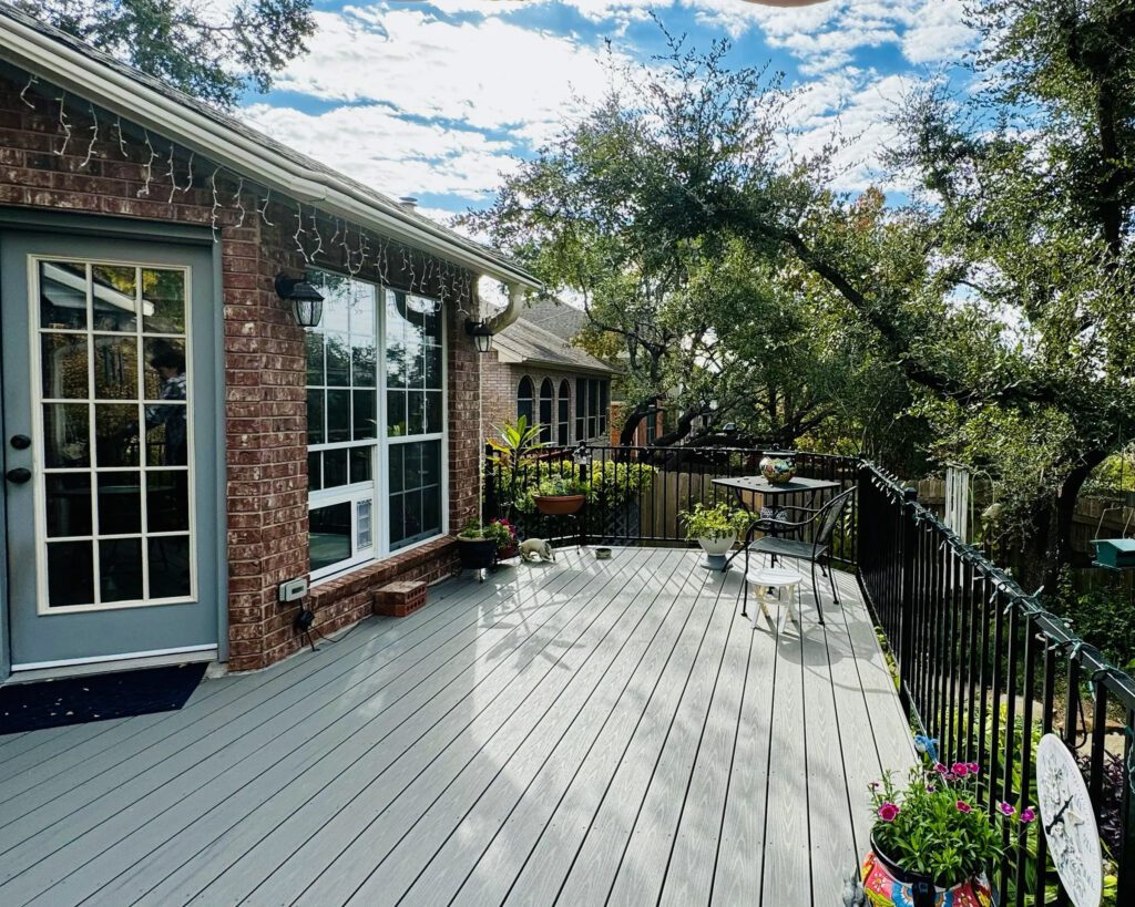 Custom backyard deck with iron railing | Trinity Fence & Deck Gallery Austin Wood deck with iron railing and potted plants — featured in our fence and deck gallery Austin