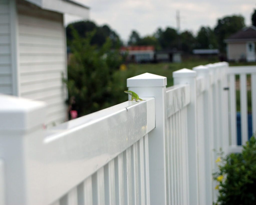 White vinyl picket fence running alongside residential sidewalk