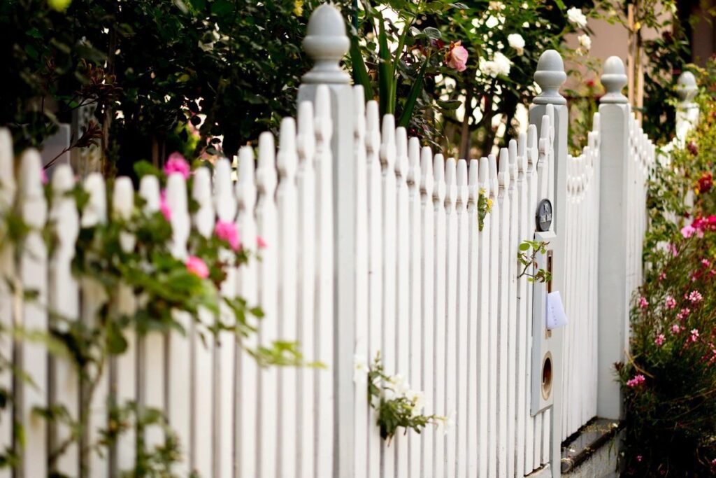 classic white picket fence with lush landscaping