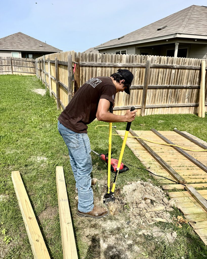 Trinity Fence & Deck technician digging a new post hole as part of a fence repair and reinforcement service.