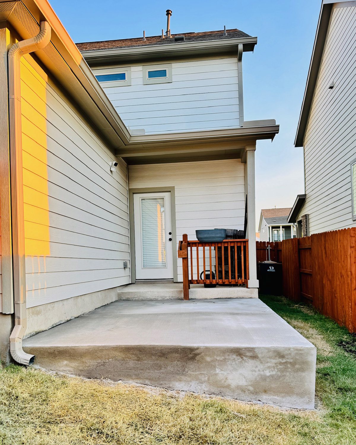 Back concrete patio with small railing and door access into the home.