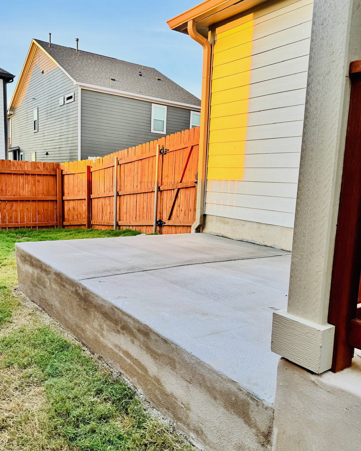 Elevated concrete patio corner with smooth finish and wooden fence backdrop.