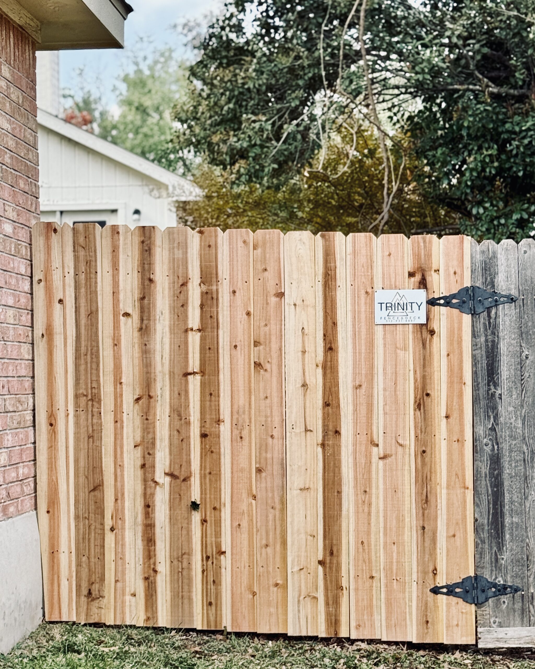 Fresh cedar privacy gate installed by Trinity Fence & Deck next to an older weathered wood fence