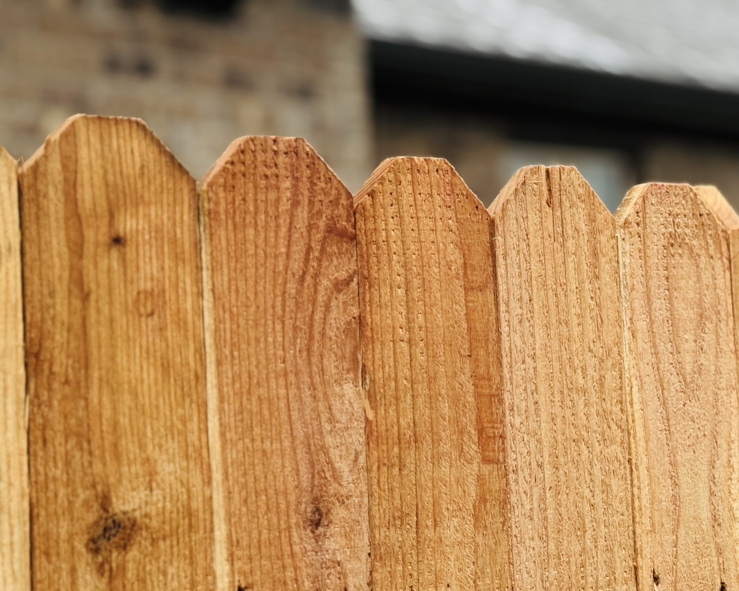 Close-up of cedar privacy fence pickets showing natural wood grain, warm cedar tones, and cleanly cut pointed tops