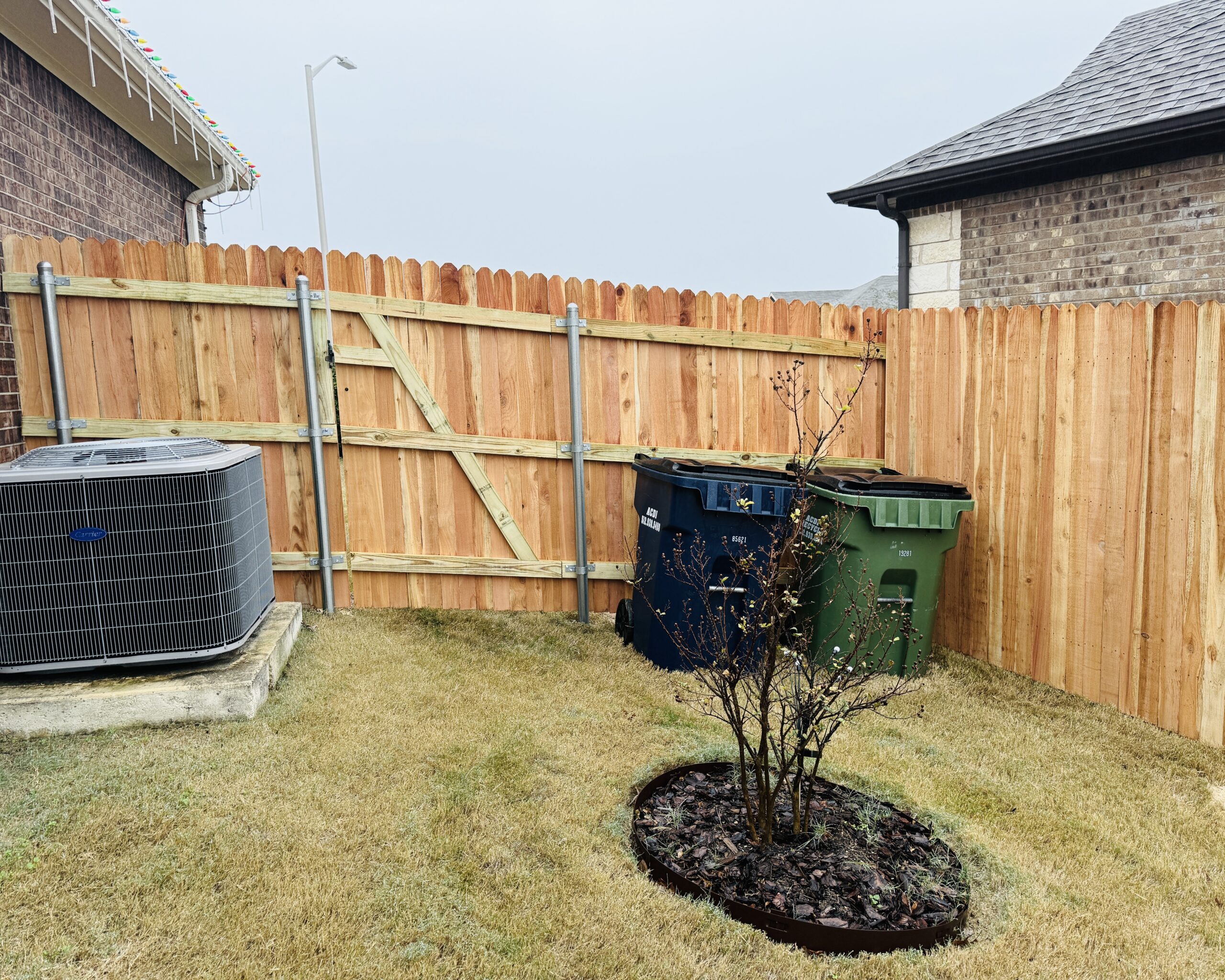 Cedar privacy fence with steel posts and reinforced gate in a residential backyard