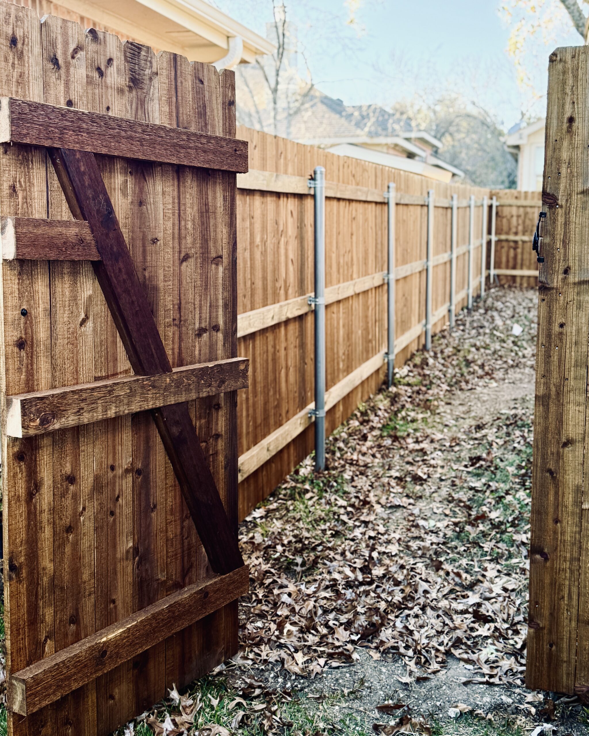 Interior view of stained wooden fence gate showing bracing and metal hardware