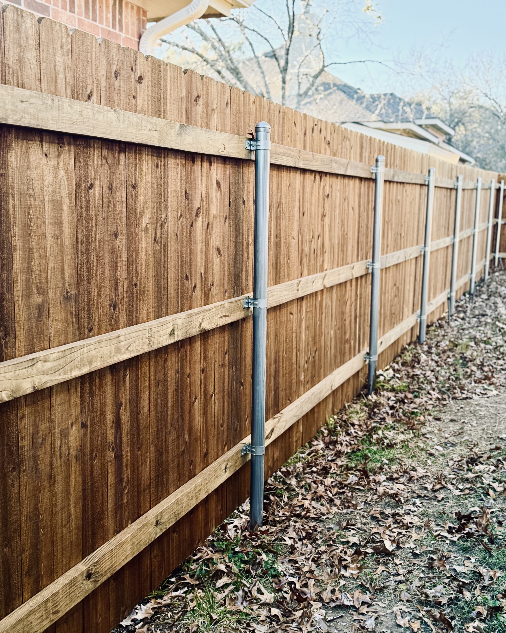 Stained wooden fence with steel posts and clean horizontal lines in residential yard