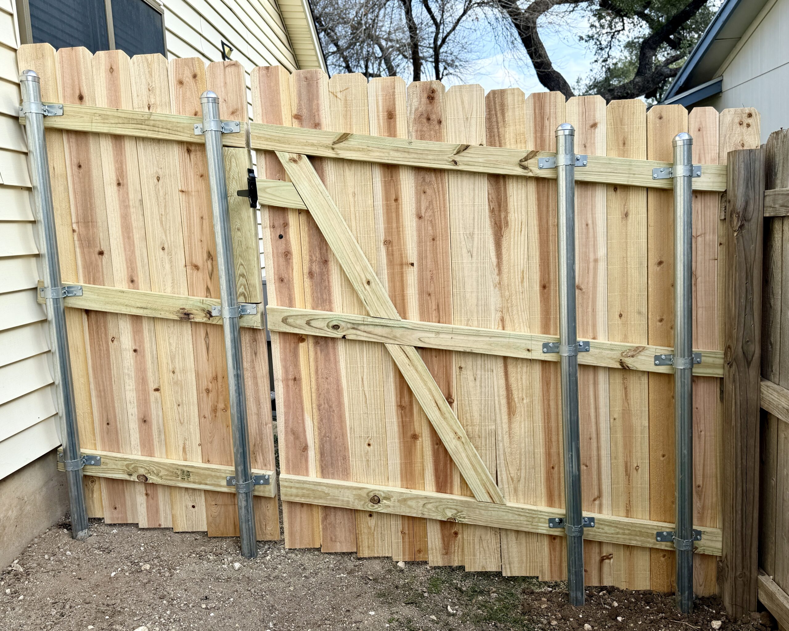 Rear view of cedar privacy fence with steel posts and reinforced gate framing